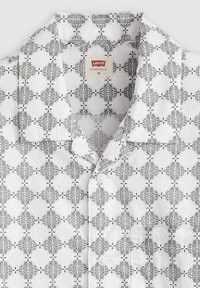 Camisa de manga corta en algodón blanco con un diseño abstracto en negro, con un frente abotonado y un cuello abierto. Etiqueta de Levi's visible.