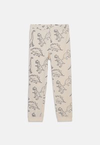 Beige Baumwollleggings mit schwarzem Dinosaurierdruck, der verschiedene Dinosaurierarten zeigt. Gummibund und taillierte Passform, glatte Textur.