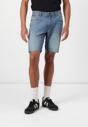Light blue denim shorts with a regular fit, five-pocket design, and a straight cut, paired with black sneakers and white crew socks.