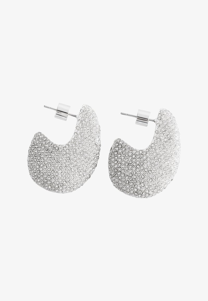 Boucles d’oreilles clous en forme de croissant ton argent avec des motifs circulaires texturés couvrant la surface, dotées de tiges droites et de fermoirs papillon.