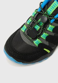Svart sneakers med mesh og syntetisk materiale, med lysegrønne og blå detaljer, et elastisk snøringssystem, og en teksturert såle.
