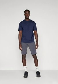 Nodilzt zils īsām piedurknēm krekls un pelēkas šortas. Krekls ir pieguloša stila; šortām ir sānu kabatas. Aksesuāri ietver baltas zeķes un melnas kurpes.