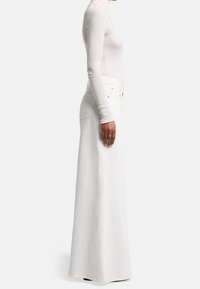 Witte denim maxi rok met een hoge taille, rechte silhouet en subtiele stiksels. Gecombineerd met een getailleerde, ribbelige lange mouw top.