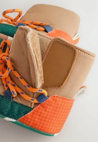Beige Stoffstiefel mit orangen Schnürsenkeln, grünen und orangefarbenen Akzenten. Weiche Innenpolsterung, strukturierte braune Einlage und gepolsterter Schaft für zusätzlichen Komfort.
