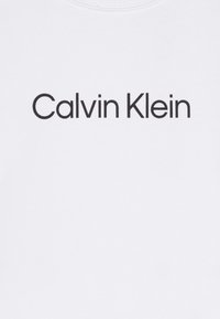 Fehér pamut pulóver fekete "Calvin Klein" logóval, amely sans-serif betűtípussal készült, a fronton középre helyezve. Klasszikus környakú fazon.