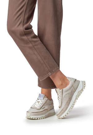 Lichte beige chunky sneakers met een gestructureerde stof en een contrasterende witte rubberen zool. Voorzien van opvallende veters en branding op de tong.
