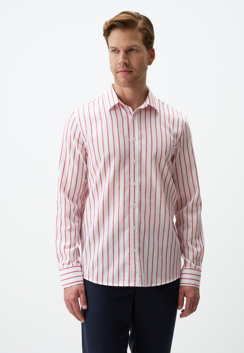 Chemise blanche à manches longues avec de fines rayures rouges, de conception boutonnée et avec un col classique. Le tissu semble léger et texturé.