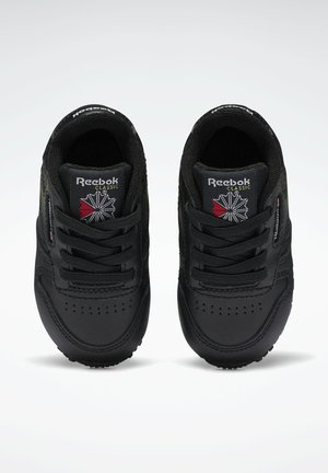 Baskets Reebok Classic noires avec un upper en cuir lisse, un design à lacets, un col rembourré et un logo sur la languette. Forme de bout rond et semelle texturée.