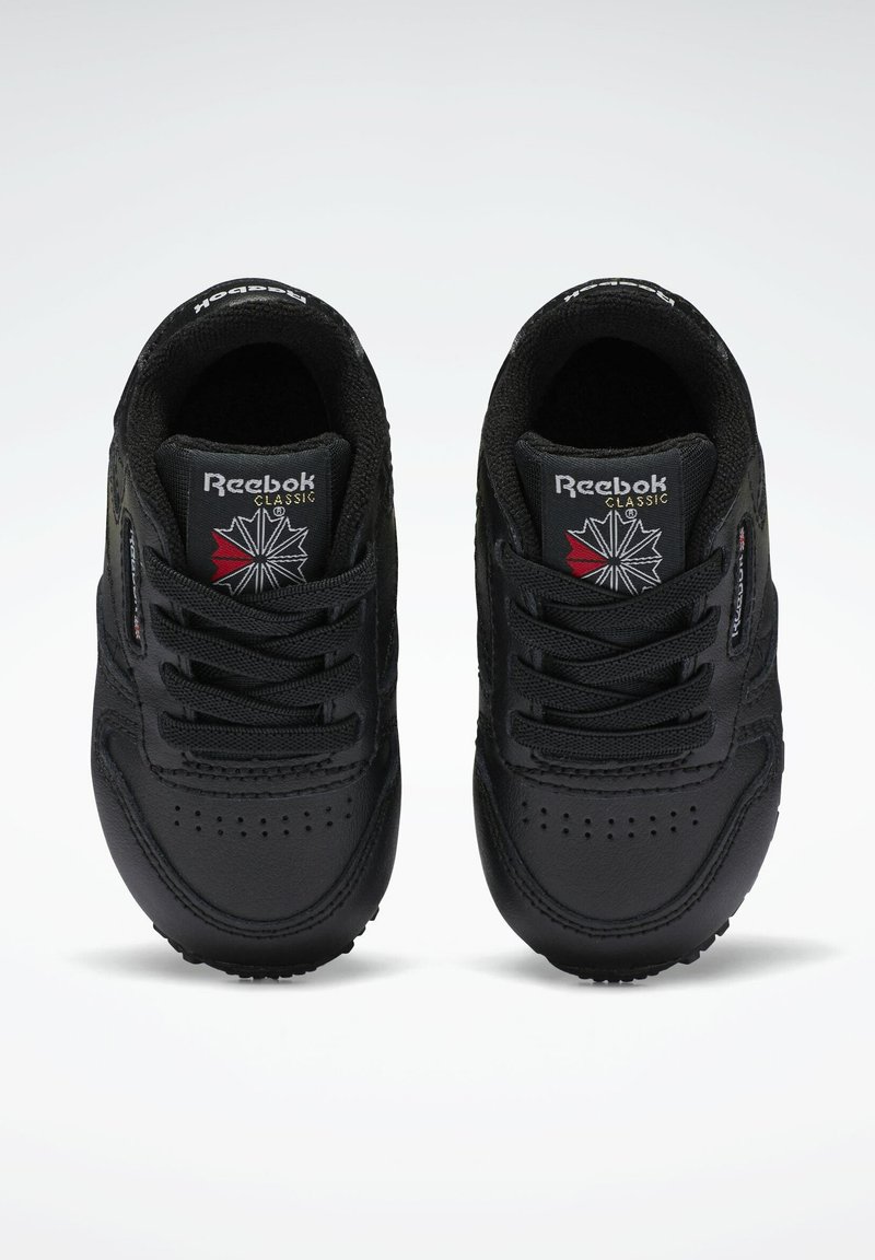Svart Reebok Classic sneakers med övre i slätt läder, snörningsdesign, vadderad krage och logotypdetalj på tungan. Rund tåform och texturerad sula.