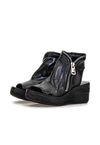 Czarne skórzane sandały na koturnie z otwartym palcem, z zamkiem po boku, z teksturowaną czarną podeszwą i gładkim wierzchem.