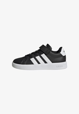 Sneaker Adidas bianco e nero con strisce bianche, chiusura con lacci davanti e strap in velcro su suola bianca, vista laterale.