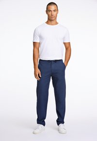 Marinblå linnebyxor med dragsko och avspänd passform, tillsammans med en enkel vit t-shirt med rund hals och vita sneakers.