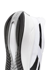 Suela de zapato deportivo en blanco y negro con goma texturizada, que presenta un diseño liso y moldeado y un logo embosado en el área del talón.