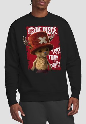 Schwarzer Sweatshirt mit einem bunten Grafik eines Cartoon-Charakters mit Geweih und rotem Hut, auf einem roten Hintergrund mit weißem Text.