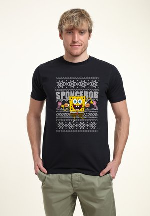 Czarny bawełniany t-shirt z kolorową grafiką SpongeBoba Kanciastoportego, wzorami śnieżynkami i wyrazistym tekstem nad projektem postaci.
