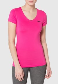 Pink fitted t-shirt with short sleeves and a V-neck. Features a black Nike logo on the left chest. Smooth fabric, minimalistic design.