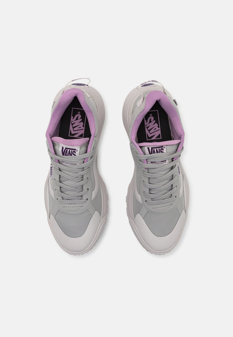 Zapatillas de deporte gris claro con una malla texturizada y acentos suaves, que cuentan con un forro morado y una plantilla de marca, diseño de cordones y punta redondeada.