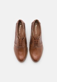 Zapatos de cuero marrón con un acabado liso y paneles laterales texturizados. Cuentan con cordones y un diseño de puntera redondeada. Talla 40 visible en el interior.