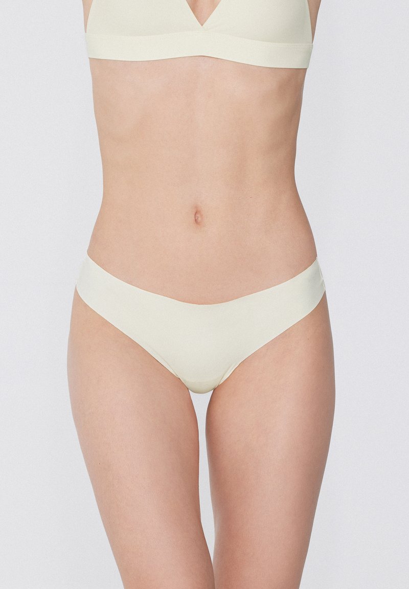 Lichtgele naadloze bh en bijpassende slip gemaakt van gladde, rekbare stof, gekenmerkt door een eenvoudig ontwerp met een V-vormige halslijn.
