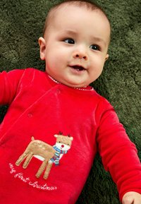 Roter Baby-Overall aus weichem Stoff mit einem bestickten Rentier, das einen Schal trägt, und dem Text "mein erstes Weihnachten" in Weiß.