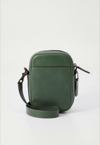 Grön läderväska med rundade kanter, slät textur, dragkedjestängning och avtagbar rem. Har präglad logotyp och metalldetaljer.