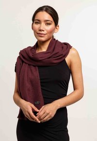 Sciarpa bordeaux con una leggera brillantezza, texture morbida e design drappeggiato. Presenta un'etichetta con il logo e uno stile versatile e fluido.