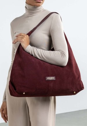 Burgunderfarbene Wildleder-Schultertasche mit einem lässigen Design, goldenen Hardware-Akzenten und einem kleinen Logo-Tag. Weiche Textur und geräumige Form.