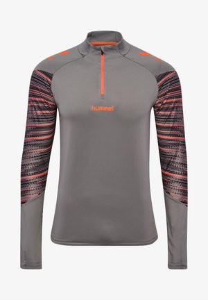 Camisa deportiva de manga larga gris con cuello de media cremallera, que presenta detalles en naranja y mangas con un patrón de líneas horizontales y puntos.