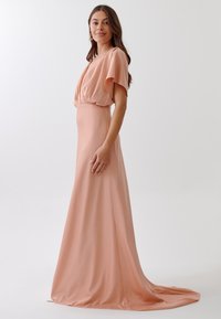 Long, blush pink dress in a soft, smooth fabric with flutter sleeves and a flowing skirt, featuring a fitted bodice and train.
