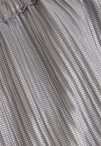 Srebrna tkanina o teksturze z pionowymi paskami i małymi punktowymi wzorami. Miękki, gładki materiał o delikatnym połysku.