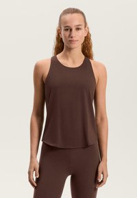 Rjava majica brez rokavov z zaobljenim izrezom okoli vratu in dizajnom racerback. Tkanina je videti gladka in lahka, dopolnjujoča ujemajoče legice.