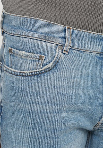 Light blue denim jeans with a distressed texture, featuring a front pocket, metal rivets, and contrast stitching along the seams.