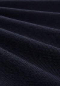 Tessuto in maglia blu scuro con una superficie texture, caratterizzato da pieghe ondulate parallele, che evidenziano la sua qualità morbida e elastica.