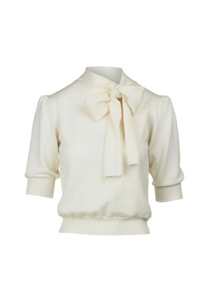 Pull en tricot color crème avec des manches courtes bouffantes, un col montant et un grand nœud décoratif au col. Ourlet et poignets côtelés ajustés.