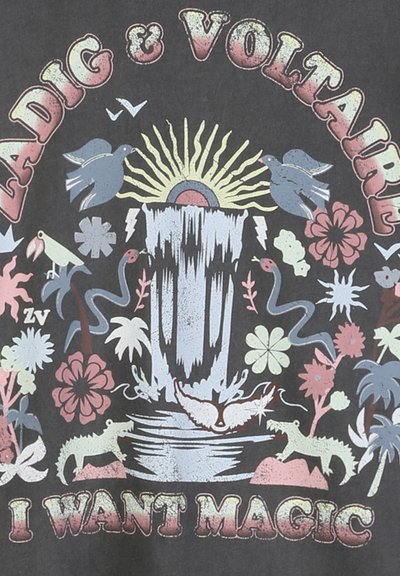 Καταρράκτης με ήλιο, πουλιά, φίδια, λουλούδια και κροκόδειλους· κείμενο «Zadig & Voltaire» από πάνω και «I Want Magic» από κάτω σε σκούρο φόντο.