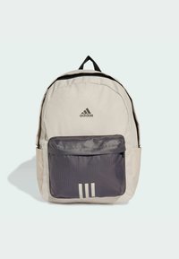 Zaino beige con una tasca frontale grigia, caratterizzato dal logo Adidas e tre strisce bianche. Realizzato in un tessuto resistente con spallacci regolabili.