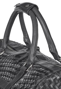 Musta nahkainen matkalaukku, jossa on kudottu pinta, kaksinkertaiset kahvat nahkatuella ja hopeiset metalliosat. Läheltä otettu kuva.