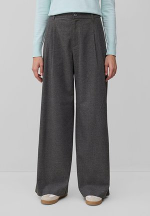 Pantaloni grigi a gamba larga con pieghe, realizzati in un tessuto testurizzato. Chiusura con bottone in vita, abbinati a sneaker bianche con suole beige.