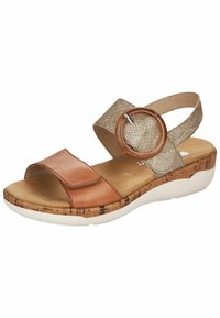 Sandale marron et dorée avec une sangle en cuir et une bande en tissu texturé. Présente un accent circulaire et une semelle en liège clair.