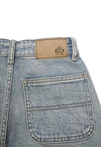 Hellblaue Denim-Jeans mitgestickten Details, einem rechteckigen braunen Lederpatch am Bund und einer Gesäßtasche.
