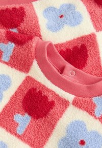 Fleece-vaate, jossa on ruudullinen kuvio punaisilla tulppaaneilla ja sinisillä kukilla, miedon pehmeällä pinnalla ja vaaleanpunaisella ribbineckillä.