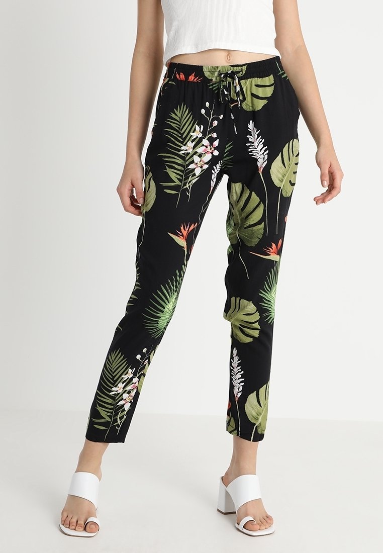 Zwarte joggerbroek met een tropisch bladeren- en bloemenpatroon, voorzien van een elastische tailleband, trekkoord en taps toelopende pasvorm.