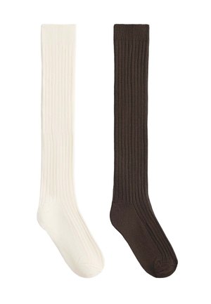 Une chaussette longue blanche et une chaussette longue brun foncé côtelées placées côte à côte sur un fond blanc.