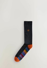 Calzino nero con tallone e punta arancioni, caratterizzato da strisce orizzontali in viola, verde e blu lungo il lato. Tessuto intrecciato con logo arancione.