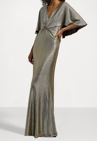 Metalická zlatá večerní róba s hlubokým V výstřihem a plášťovými rukávy, se zkrouceným uzlem v oblasti pasu. Hladká, třpytivá textura.