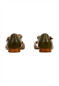 Zapatos de cuero verde vistos por detrás, con detalles recortados, un tacón de madera bajo y un acento de hebilla lateral para ajustabilidad.