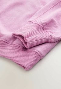 Helles rosa Sweatshirt mit gerippten Bündchen, das eine glatte Textur und ein einfaches Design zeigt. Mit sichtbaren Nähten entlang der Kanten.