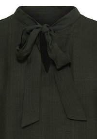 Blouse vert foncé avec un col rond et un nœud noué à l’ouverture avant du col.