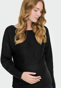 Maglione nero lavorato a maglia con scollatura ampia, maniche lunghe, tessuto testurizzato e piccoli dettagli a fantasia sulle maniche. Design aderente.