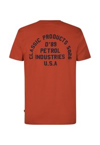 Krátký rukáv oranžové tričko vyrobené z bavlny, na zádech s tmavě námořnickým sítotiskem obsahujícím text "PETROL INDUSTRIES" a další detaily.